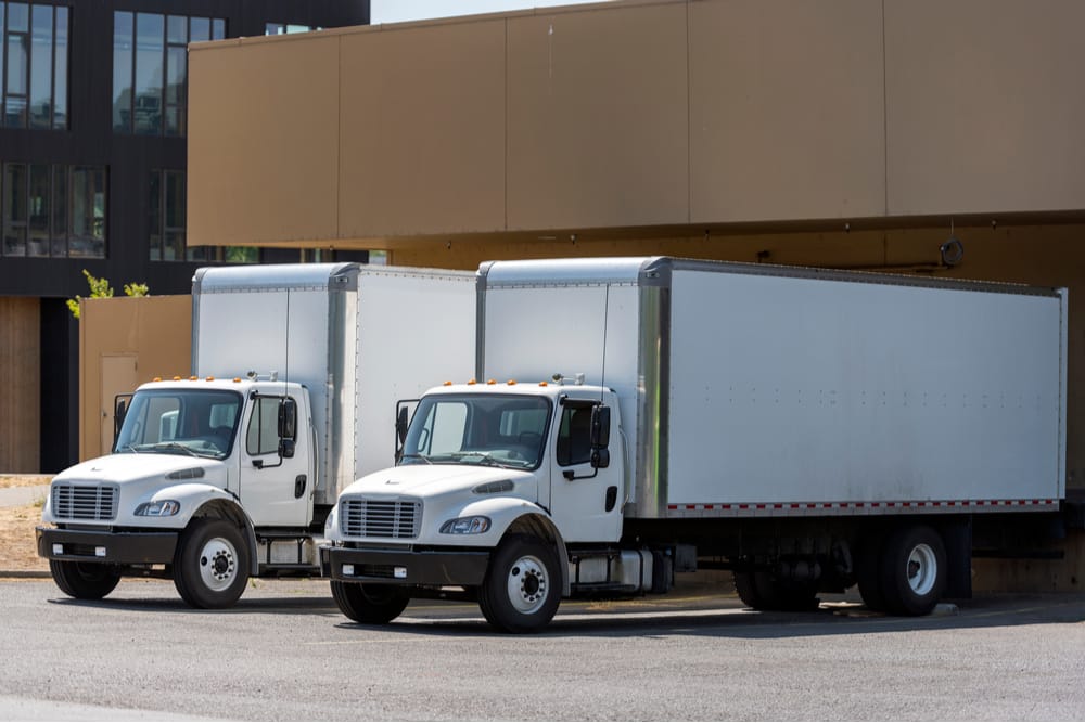 Two white box trucks, also called straight trucks